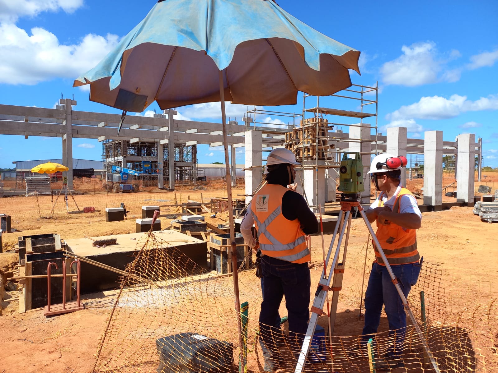 Equipe de topografia trabalhando em canteiro de obras com equipamentos de precisão